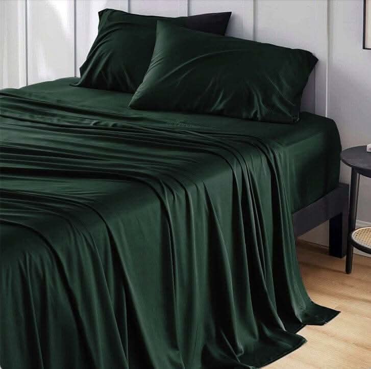 Elegant dark green bamboo bed sheets draped over a bed, creating a soft and luxurious look. These bamboo sheets are ultra-soft, breathable, and hypoallergenic, offering exceptional comfort and durability for a restful sleep.
